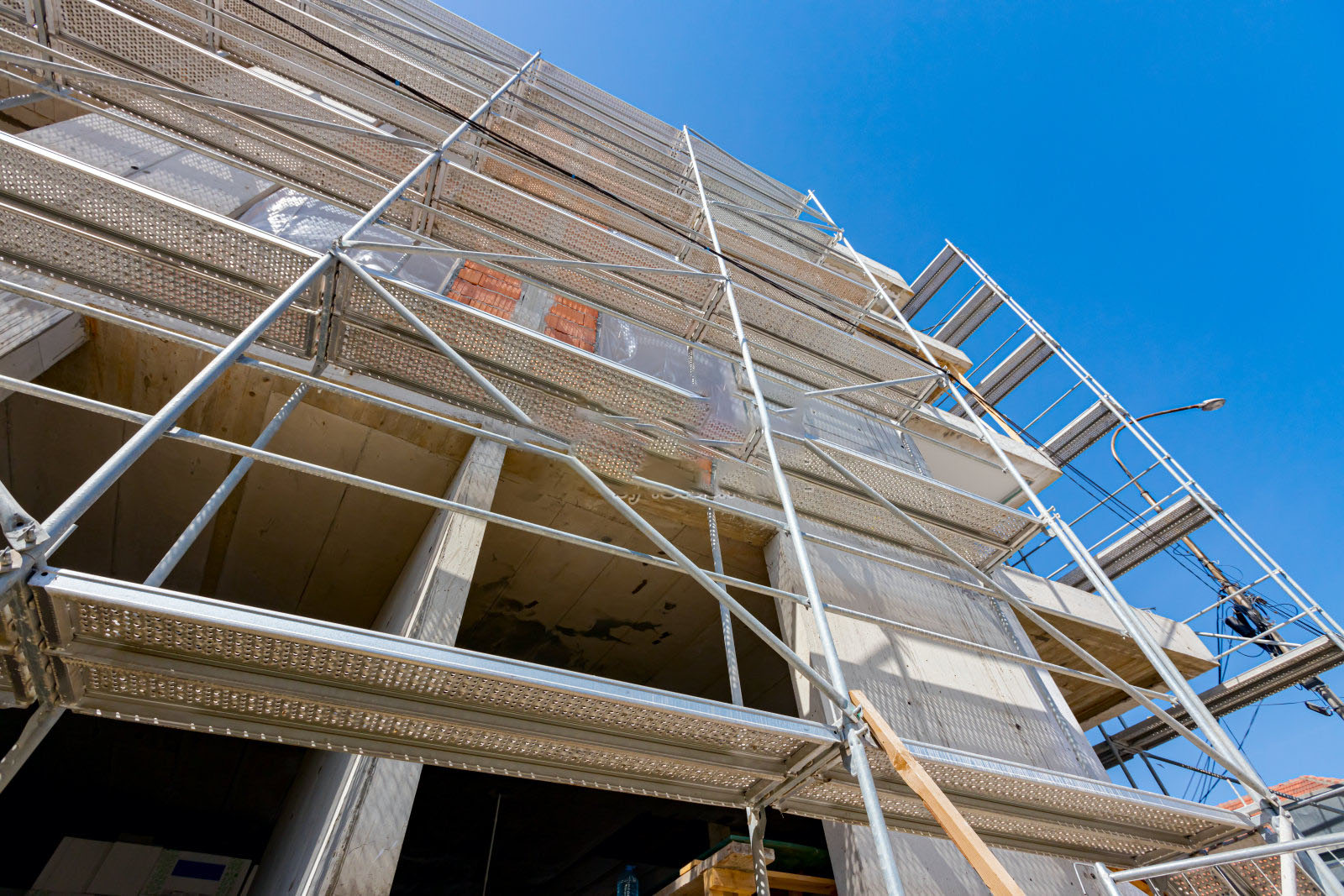 View from below on scaffold placed against unfinished edifice, new residential building under construction.