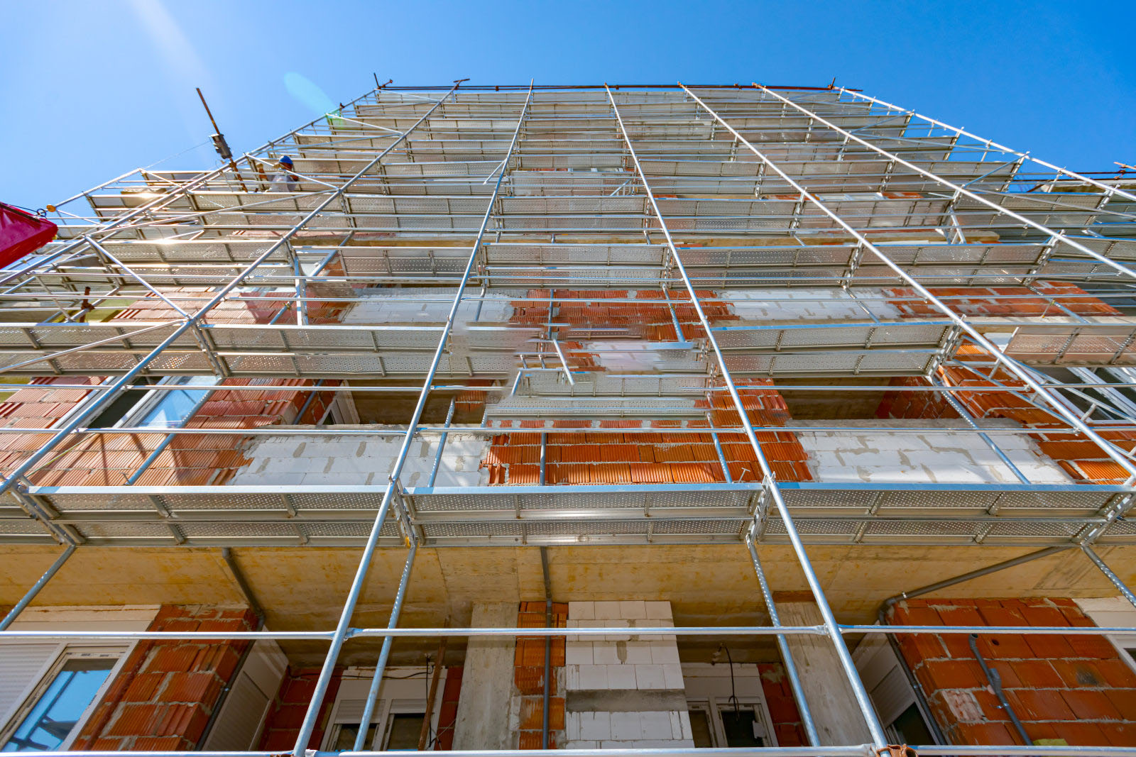 View from below on scaffold placed against unfinished edifice, new residential building under construction.